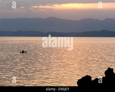 Un canot à rames homme à travers le lac Kivu au coucher du soleil, Goma, dans la province du Nord Kivu, République démocratique du Congo ( RDC ), l'Afrique Banque D'Images