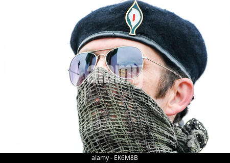 Un homme masqué portant un scrim sur sa bouche, lunettes de soleil et un béret noir fait partie d'une commémoration Républicaine Irlandaise Banque D'Images