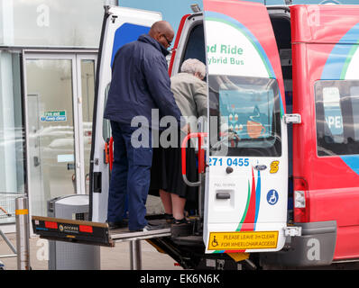 Une vieille dame sur un pont élévateur à l'arrière d'une mobilité park and ride minibus hybride dans un centre commercial à Coventry. Banque D'Images