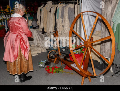 Femme (50-60 ans) spinner en costume traditionnel à l'aide d'un conduit de la roue tournante à tourner l'alpaga laine Banque D'Images