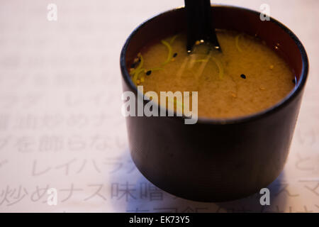 Un gros plan d'un noir et rouge bol avec de délicieux soupe miso et cuillère Banque D'Images