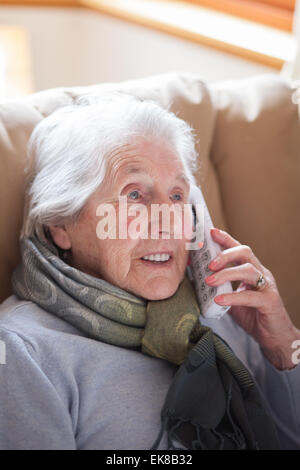 Vieille dame assise dans un fauteuil à parler au téléphone Banque D'Images