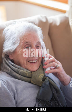 Vieille dame assise dans un fauteuil à parler au téléphone Banque D'Images