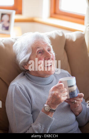 Vieille dame se détend dans un fauteuil avec une tasse de thé Banque D'Images