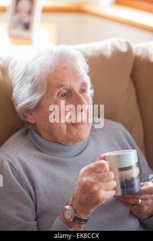 Vieille dame se détend dans un fauteuil avec une tasse de thé Banque D'Images