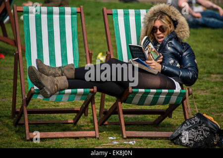 Londres, Royaume-Uni. Le 08 Avr, 2015. Une femme jouit d'une copie de Roméo et Juliette dans un rebord de la fourrure parka et shorts. Le soleil du printemps fait sortir les travailleurs et les touristes à l'heure du déjeuner. Ils vous détendre dans les chaises longues ou même les utiliser comme bureaux de plein air. Green Park, Londres, 06 mai 2015. Crédit : Guy Bell/Alamy Live News Banque D'Images