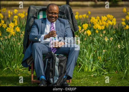 Londres, Royaume-Uni. Le 08 Avr, 2015. Un employé de bureau est heureux de son déjeuner en face d'une mer de jonquilles. Le soleil du printemps fait sortir les travailleurs et les touristes à l'heure du déjeuner. Ils vous détendre dans les chaises longues ou même les utiliser comme bureaux de plein air. Green Park, Londres, 06 mai 2015. Crédit : Guy Bell/Alamy Live News Banque D'Images