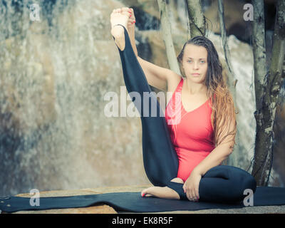 Jeune femme est la pratique du yoga near waterfall Banque D'Images
