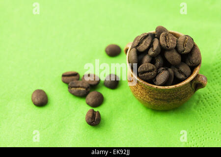 Petit pot avec les grains de café sur fond vert Banque D'Images