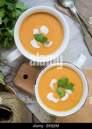 Deux tasses blanc avec vegan (végétarien) Soupe crème de potiron au lait de coco, servi avec du persil, vu de dessus. Banque D'Images