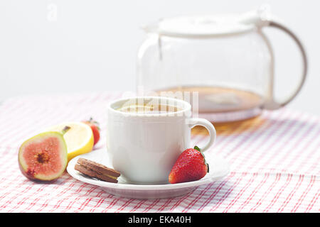 Tasse de thé, cookie, fig et les fraises sur une plaque Banque D'Images