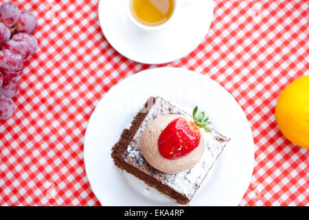Beau gâteau avec fraise, mandarine, raisin et thé sur plaid Banque D'Images