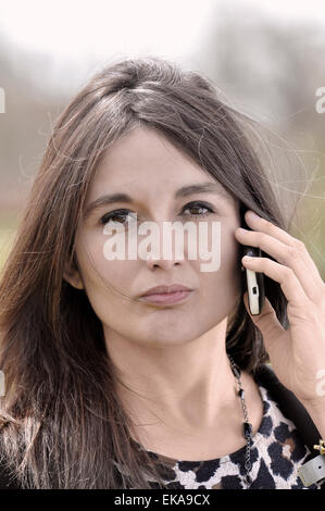 Portrait d'un Long haired Woman talking on a mobile phone Banque D'Images
