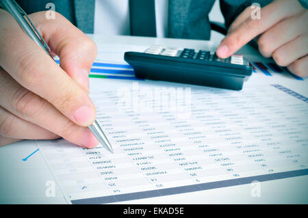 Libre d'un jeune homme d'chèques comptes avec une calculatrice dans son bureau Banque D'Images