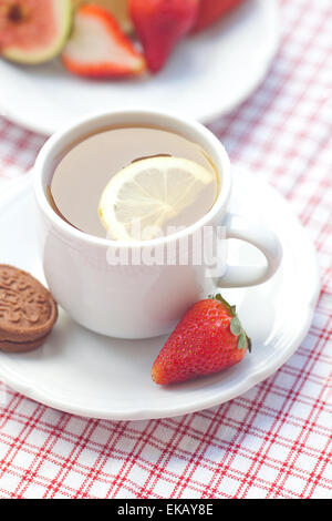 Tasse de thé, cookie, fig et les fraises sur une plaque Banque D'Images