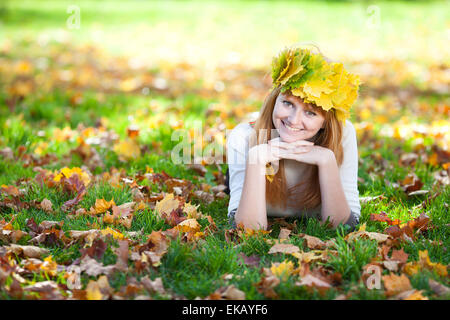 Jeune rousse adolescent femme dans une guirlande de feuilles d'érable couché o Banque D'Images