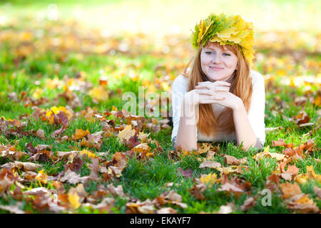 Jeune rousse adolescent femme dans une guirlande de feuilles d'érable couché o Banque D'Images