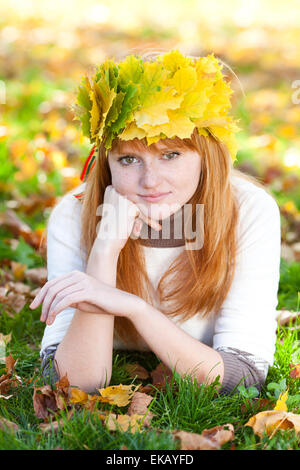 Jeune rousse adolescent femme dans une guirlande de feuilles d'érable couché o Banque D'Images