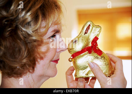 Femme mature à l'avant de manger le chocolat Lindt bunny ou le lapin de Pâques Banque D'Images