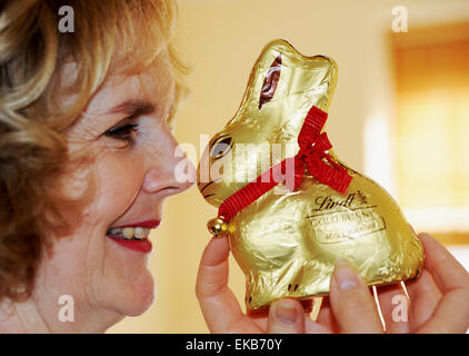 Femme mature à l'avant de manger le chocolat Lindt bunny ou le lapin de Pâques Banque D'Images