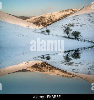 La neige a couvert la campagne d'hiver paysage lever du soleil reflétée dans lac calme Banque D'Images