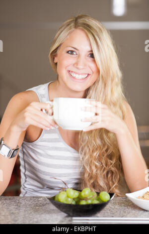 Belle jeune femme bénéficiant d'un petit-déjeuner sain dans la cuisine Banque D'Images