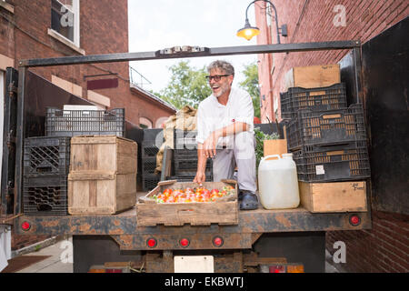 Farmer le déchargement des caisses de tomates biologiques outside grocery store Banque D'Images