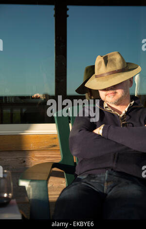 L'homme de veille sur chaise avec hat au-dessus des yeux Banque D'Images