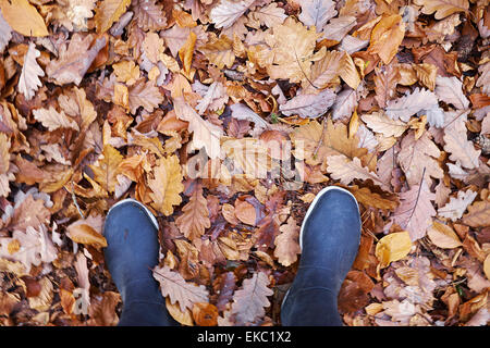 Portrait de femme en bottes de caoutchouc dans les feuilles d'automne d'échouage Banque D'Images