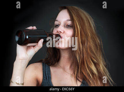 Femme ivre de boire une bière sur fond noir Banque D'Images