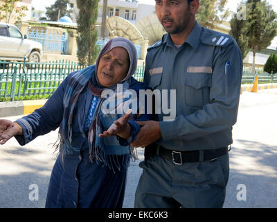 Mazar-i-Sharif, ville de l'Afghanistan. Le 9 avril, 2015. Un policier afghan assiste une femme blessés sur le site d'une attaque dans la région de Mazar-i-Sharif, ville du nord de la capitale de la province afghane de Balkh, le 9 avril 2015. Au moins quatre personnes ont été tuées et plusieurs autres blessées par des hommes armés ont attaqué le procureur d'appel provinciales immeuble de bureaux à Mazar-i-Sharif, ville du nord de la capitale de la province afghane de Balkh le jeudi, a déclaré une source officielle. (Xinhua/Azorda) Credit : Xinhua/Alamy Live News Banque D'Images