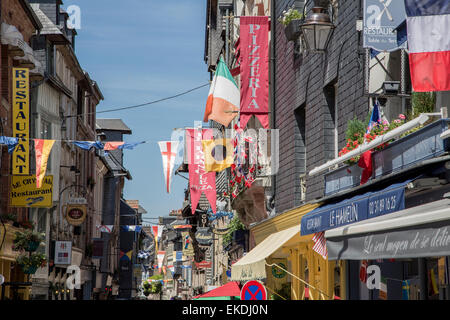 Drapeaux et Banderoles colorées ornent les bâtiments historiques dans une rue pleine de visiteurs et les étals du marché, Honfleur Normandie , France Banque D'Images