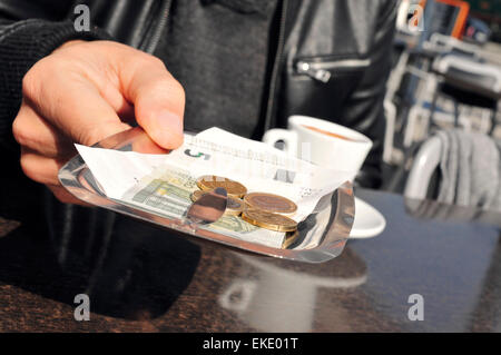 Libre d'un jeune homme avec une tasse de café paie la facture à la terrasse d'un café Banque D'Images