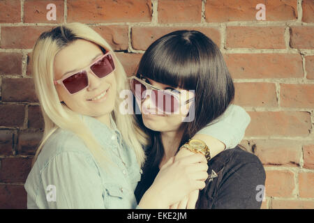 Close up fashion portrait de deux jeunes filles câlins et s'amuser ensemble, portant des lunettes élégantes, best fiend profiter du temps ensemble. Banque D'Images