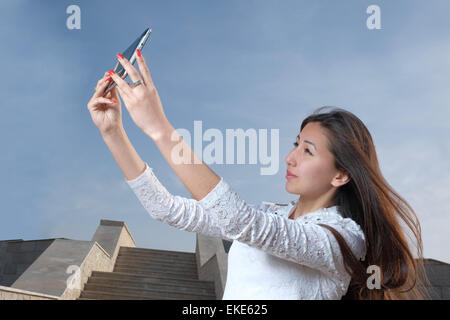 Les jeunes femmes japonaises aux cheveux longs n'afainst selfies city park en étapes et ciel bleu clair avec la lumière de brume, copyspace sur le ciel Banque D'Images