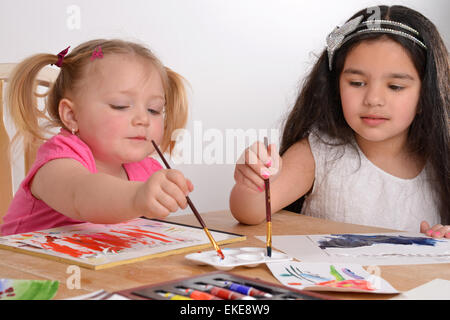 Deux jeunes filles en peinture à une table Banque D'Images