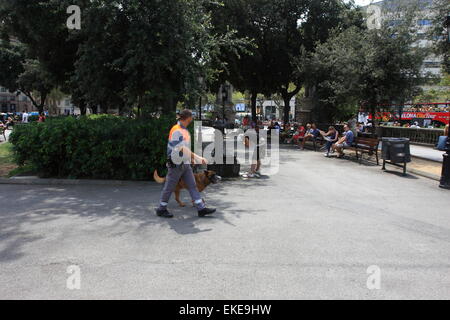 Security guard promenades à travers le carré comme un jeune homme lave ses cheveux dans la source d'eau publique à Barcelone, Espagne, 2014 Banque D'Images