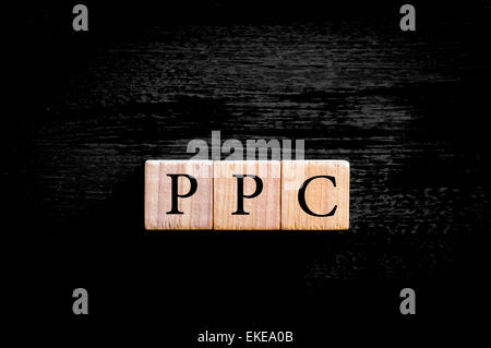 Acronyme PPC - Payer Par Clic. Petits cubes en bois avec des lettres isolé sur fond noir avec copie espace disponible. Concept d'image. Banque D'Images