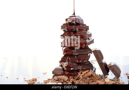 Pile de sauce au chocolat chocolat avec bec verseur verre réfléchissant sur contre fond blanc. Banque D'Images