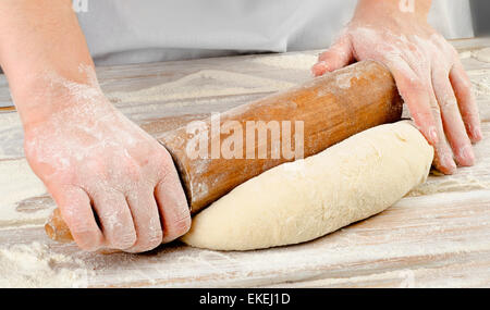Mains de la préparation de pâte avec un rouleau à pâtisserie sur une table en bois. Selective focus Banque D'Images