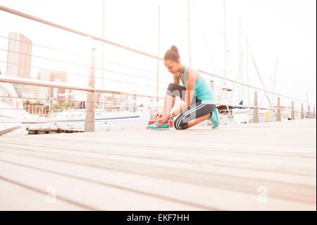 Jeune fille athlétique d'attacher ses lacets de chaussures de course pour un jogging Banque D'Images