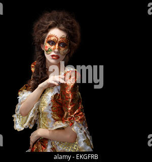 Faceart. Masque de Venise. Belle femme en robe d'époque et un masque sur son visage. Fond noir. Banque D'Images