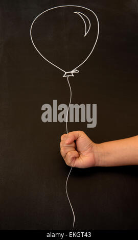 Holding balloon on blackboard Banque D'Images