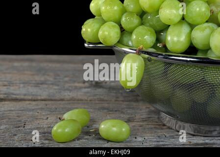 Les gouttelettes d'eau sur le raisin vert dans une passoire métallique. Banque D'Images