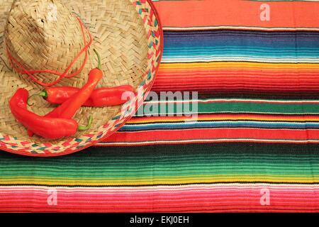 Fiesta Mexicaine traditionnelle poncho tapis piments de couleurs vives et de l'arrière-plan sombrero with copy space Banque D'Images