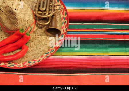 Fiesta Mexicaine traditionnelle poncho tapis piments de couleurs vives et de l'arrière-plan sombrero with copy space Banque D'Images