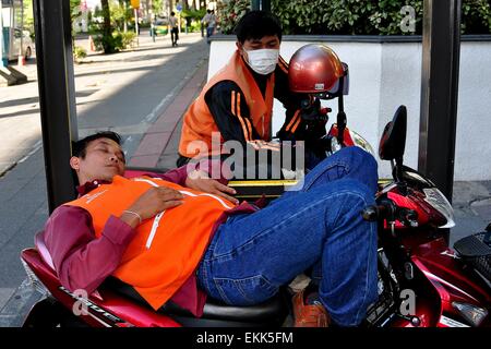 Bangkok, Thaïlande : chauffeur de taxi moto prend une sieste en attendant un tarif sur Ratchadamri Road Banque D'Images