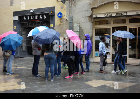 Groupe de jeunes avec des parasols debout dans la rue sur jour de pluie à Barcelone Banque D'Images