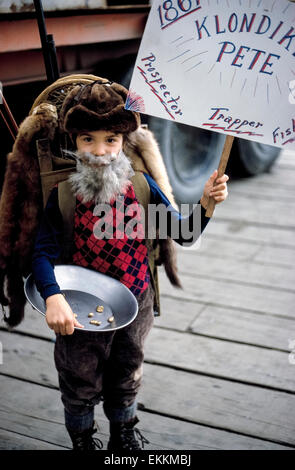 Un jeune garçon d'Alaska célèbre le 100e anniversaire de la ruée vers l'or du Klondike en s'habillant comme une bewhiskered prospecteur, trappeur et fisherman pour un quatrième de juillet parade à Wrangell, Alaska, USA. Son costume est complet avec un pan de l'extraction de l'or montrant 'gold' nuggets. Banque D'Images