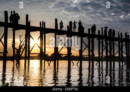 Les chiffres qui se profile, y compris une femme en short, photographier,sur le pont U Bein sur le lac Taungthaman au coucher du soleil. Banque D'Images